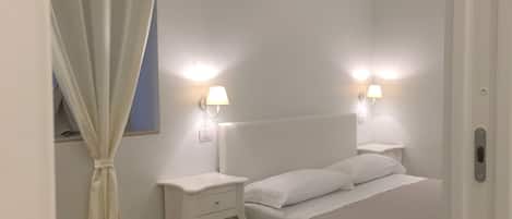 Camera da letto con un letto, due comodini, una lampada da comodino, una tenda e luci a parete.