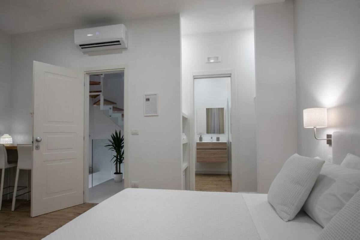 A bedroom with a bed, a desk, and an air conditioning unit.