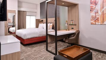Una habitación de hotel moderna con cama, escritorio, silla y una pequeña mesa de madera.