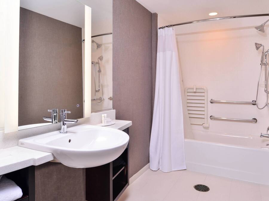A modern bathroom with a white sink, mirror, and bathtub.