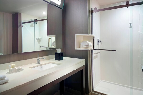 Un baño moderno con un espejo grande, dos lavamanos, cabina de ducha de vidrio y un perchero para toallas.