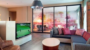Una sala de estar moderna con un televisor de pantalla plana, una mesa de centro redonda y un sofá con cojines estampados.