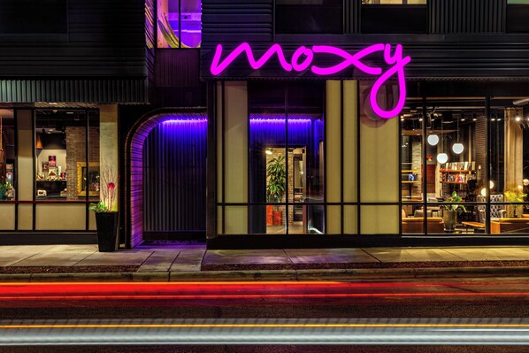 A building with a neon sign reading "mozy" and a modern interior visible through the windows.