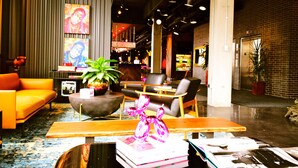 A modern lobby with a sofa, chairs, a coffee table, and a reception desk. - MOXY Minneapolis Uptown (Minneapolis)