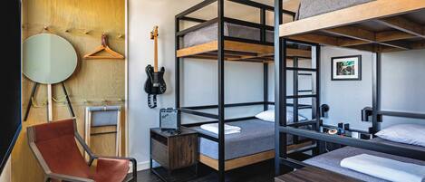 A bunk bed room with a wooden chair, a guitar, and a small table.