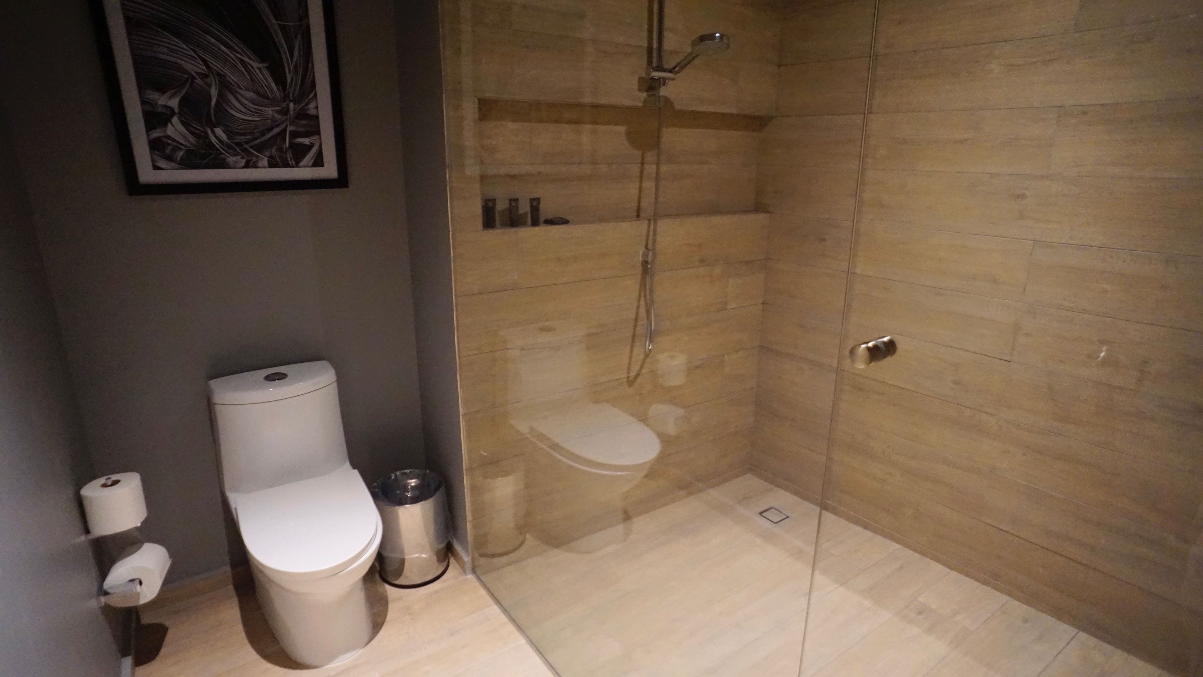 Ein modernes Badezimmer mit Toilette, einer gläsernen Dusche und Holzboden.