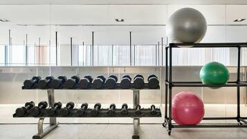 Uma academia com halteres e bolas de exercício em estantes.