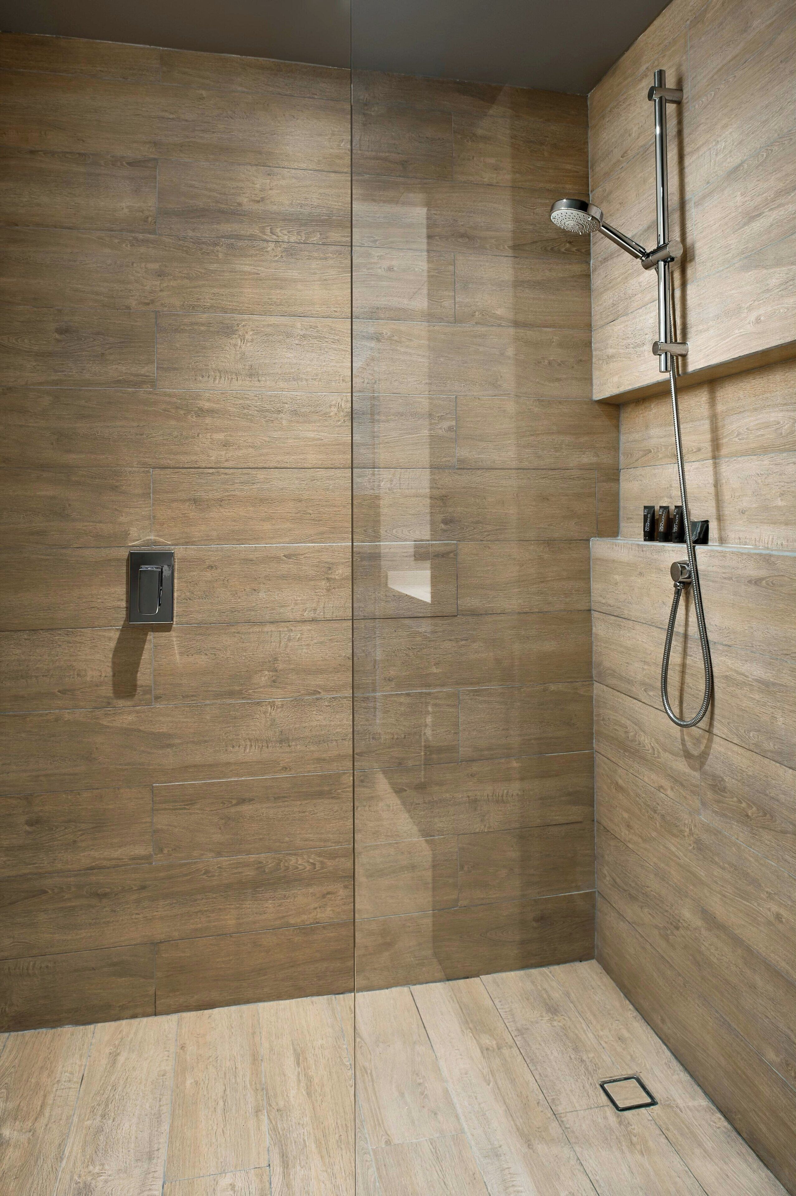 A shower with a handheld showerhead and a wall-mounted control panel.