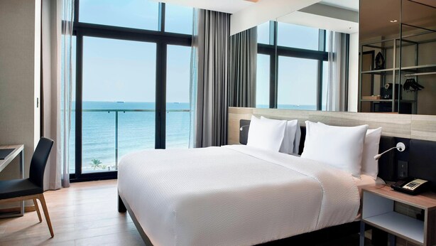 A modern hotel room with a large bed, a desk, and a view of the sea. - AC Hotel by Marriott Veracruz (Boca del Río)