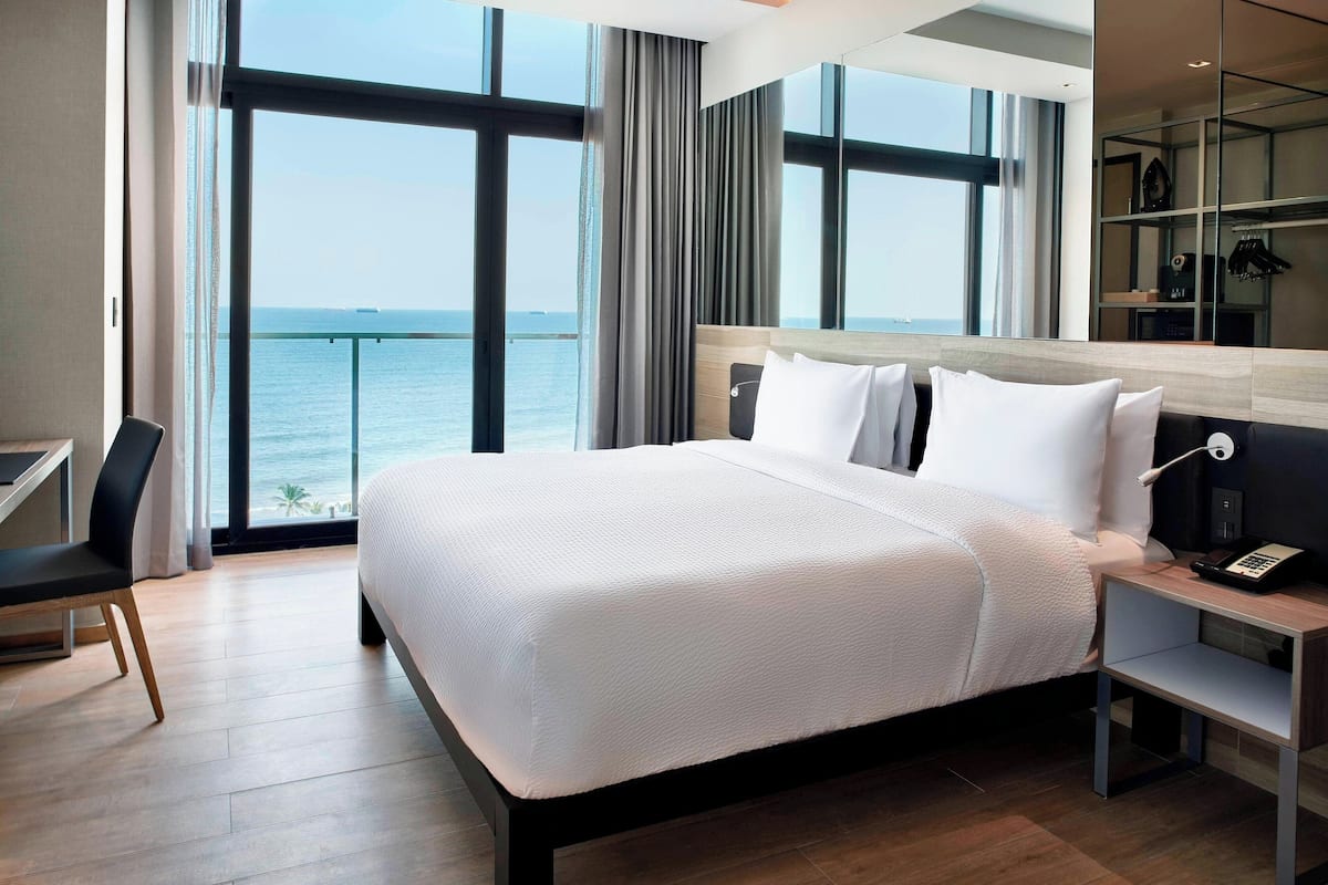 Una habitación de hotel moderna con una cama grande, un escritorio y vista al mar.