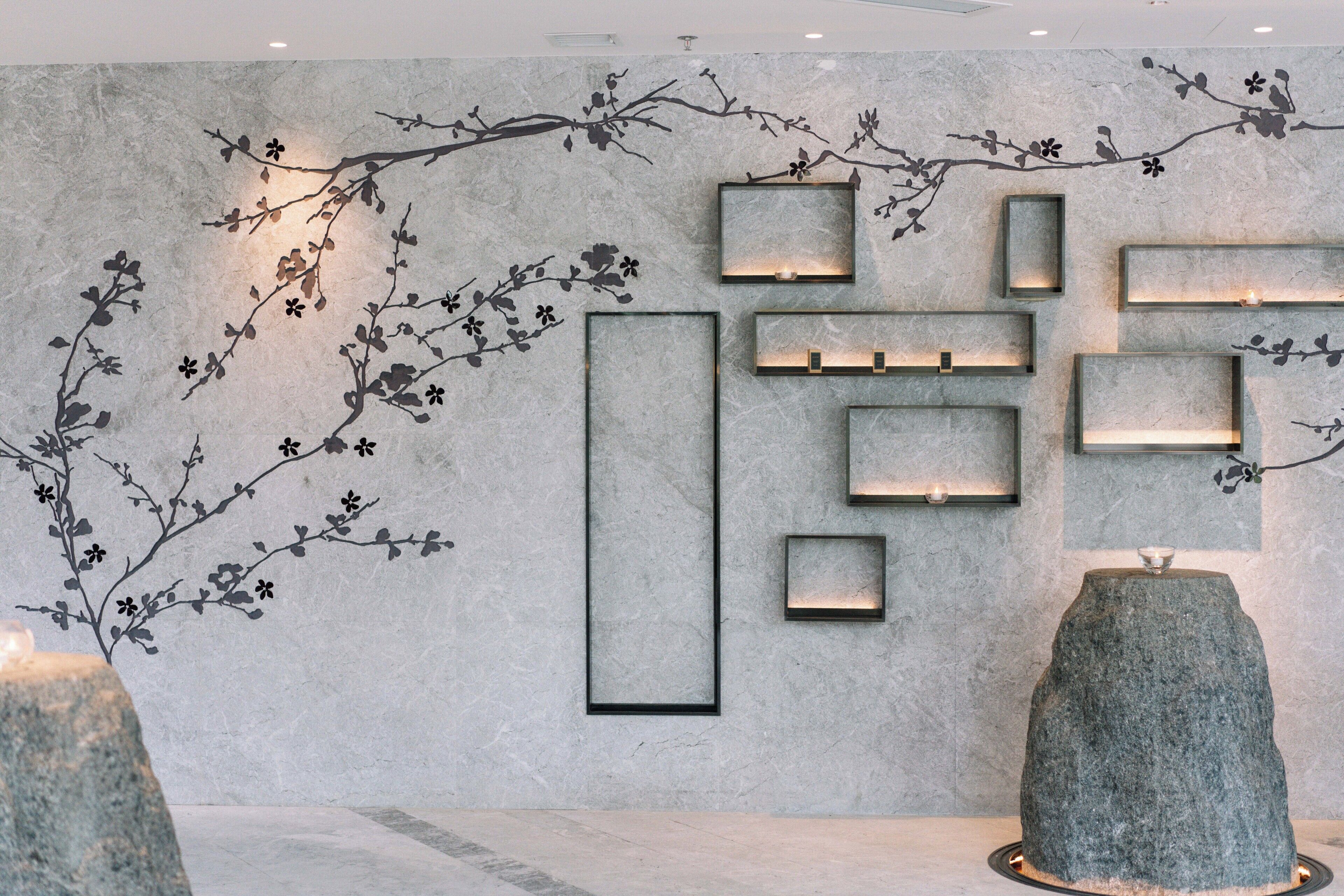 Ein modernes Interieur mit Steinwand, eingelassener Beleuchtung und einer großen Felsformation als Blickfang.