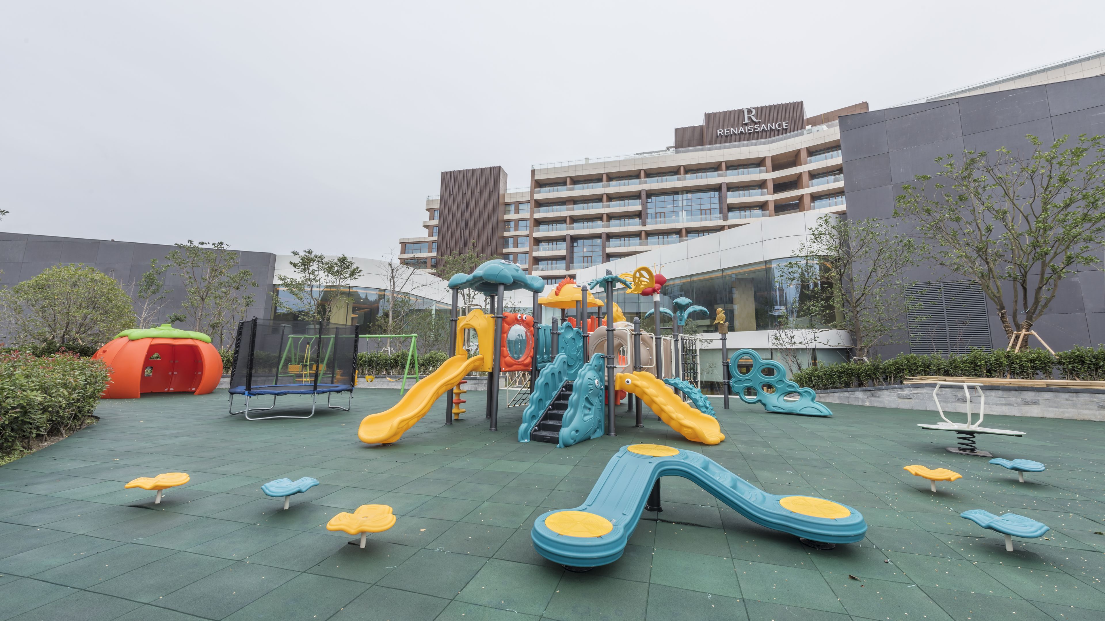 Un parque infantil con toboganes y estructuras para escalar, rodeado por un edificio con un letrero que dice 'Renaissance'.