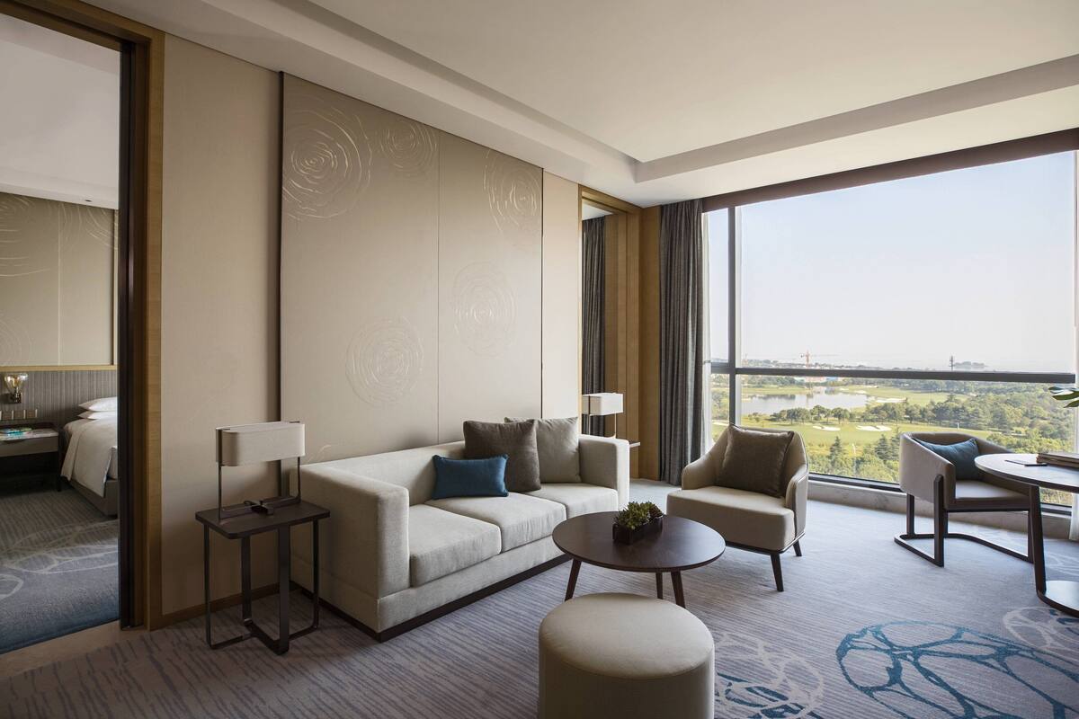 Une chambre d’hôtel moderne dotée d’une grande fenêtre donnant sur un terrain de golf.