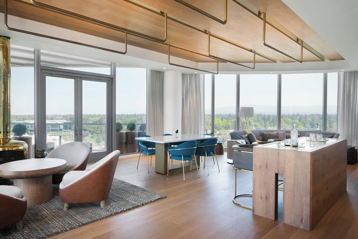A modern, spacious living area with a large dining table, comfortable seating, and large windows offering a city view.