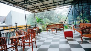 A covered outdoor seating area with checkered flooring and wooden furniture. - PIA Hotel Bandung (Bandung)