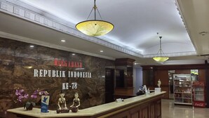 A reception desk with a marble wall, a Coca-Cola refrigerator, and a statue. - PIA Hotel Bandung (Bandung)