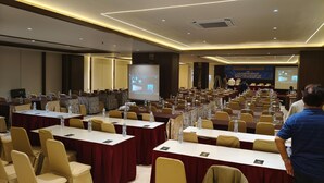 A conference room with rows of tables and chairs, equipped with water bottles and nameplates, and a presentation screen at the front. - PIA Hotel Bandung (Bandung)