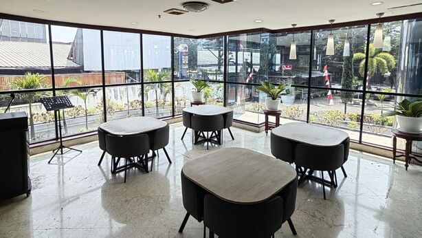 A modern indoor space with large windows, multiple tables, and potted plants. - PIA Hotel Bandung (Bandung)