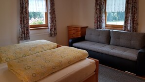 Una habitación con dos camas, un sofá, un aparador de madera y una araña.