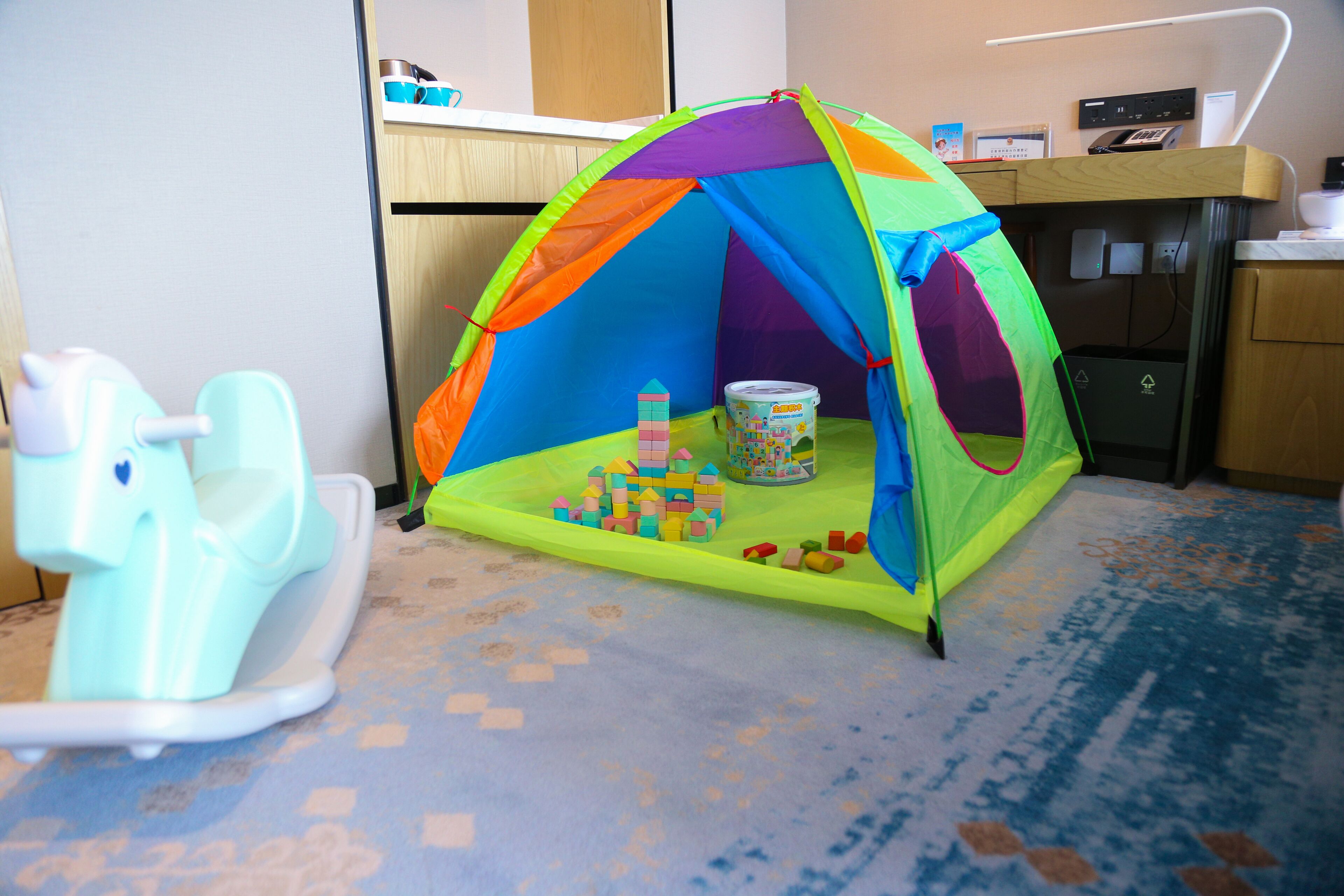 A play tent with a toy castle inside, a toy horse, and a trash bin.