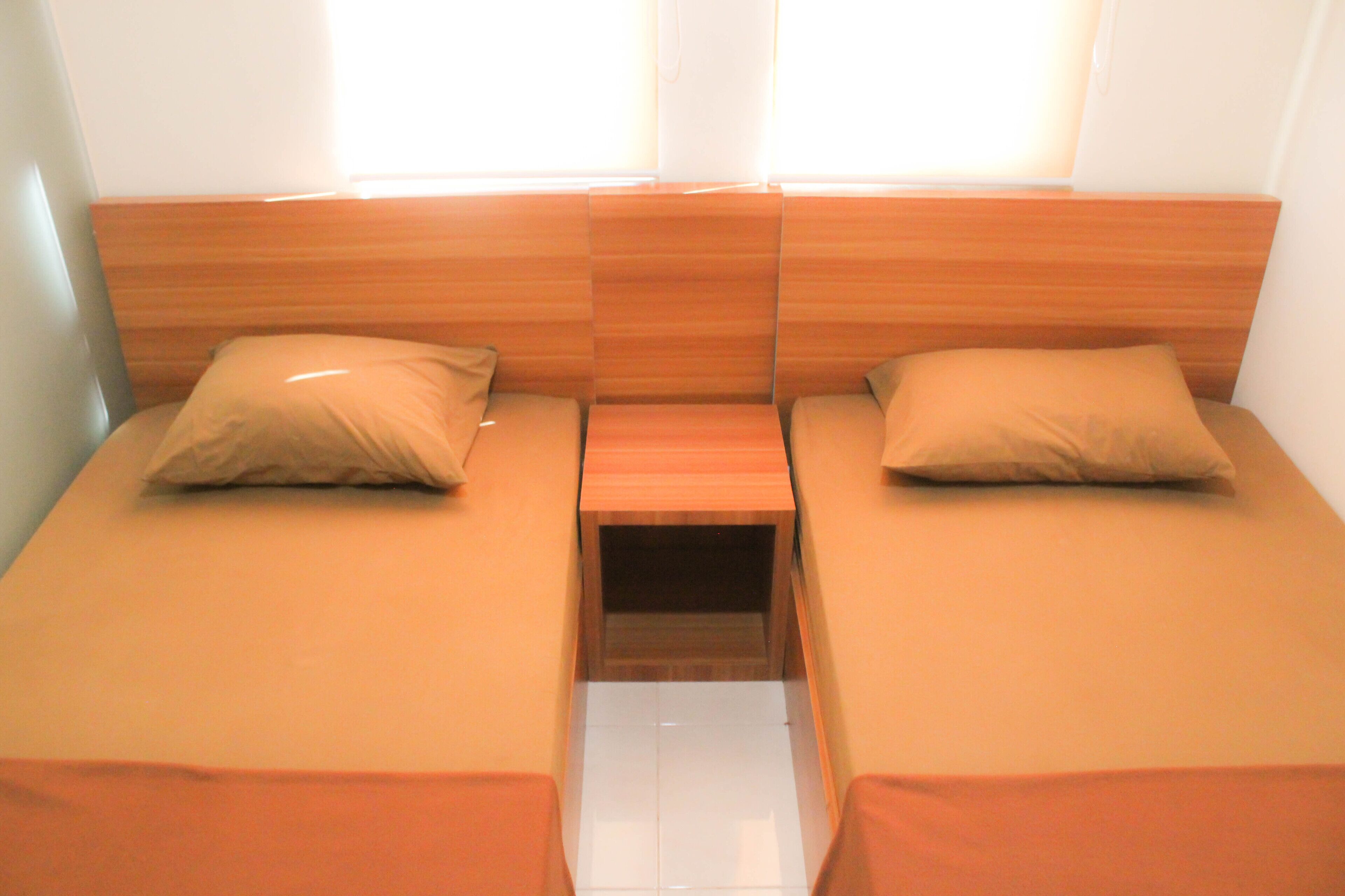A room with two single beds, each with a wooden headboard and a matching pillow.