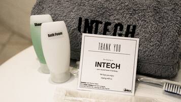 Toiletries including a bath foam bottle, a toothbrush, and a comb, along with a towel and a thank you card from INTECH.