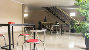A modern interior with bar stools, a staircase, and potted plants. - Intech Hostel (Bandung)