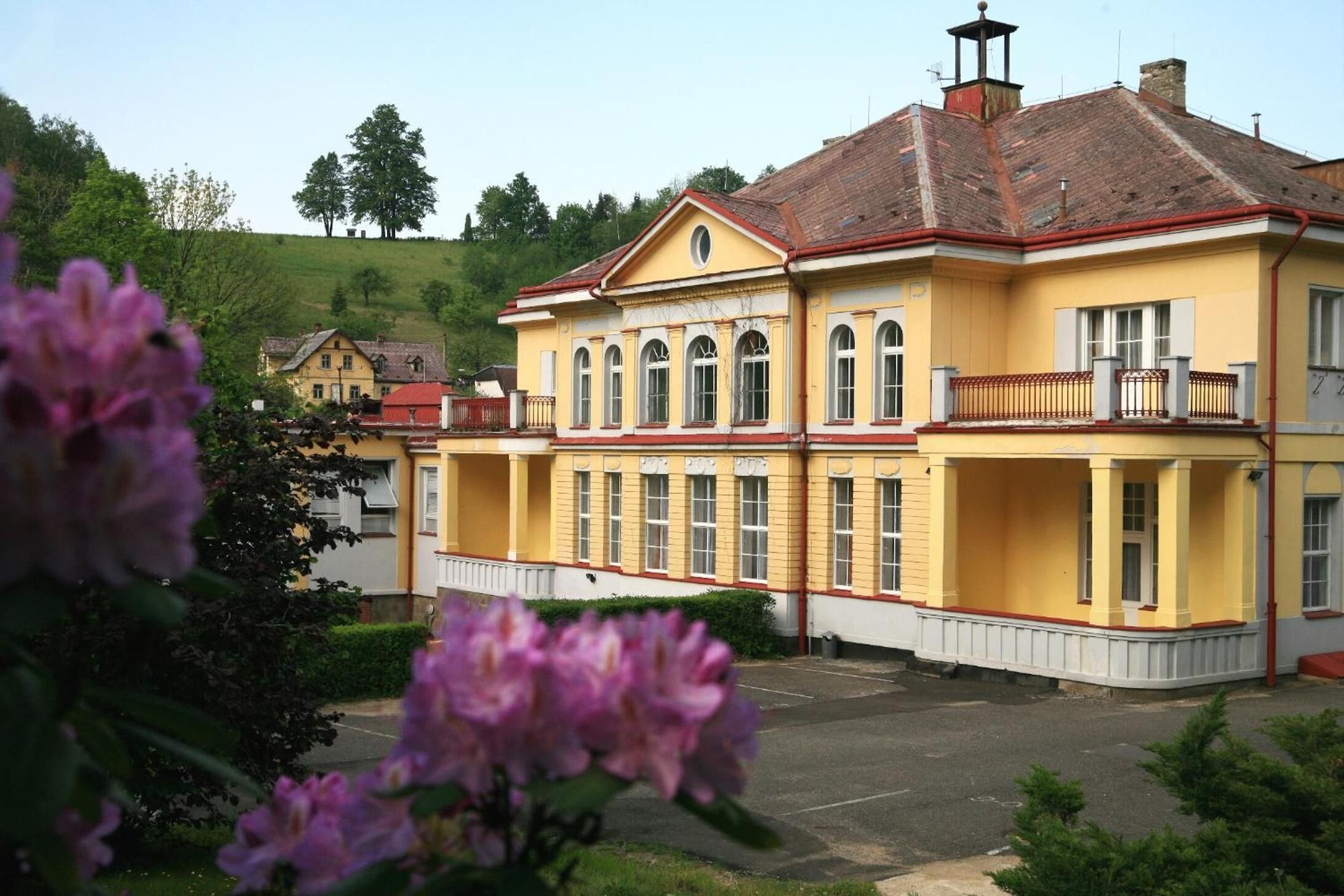 Un bâtiment jaune avec un toit rouge, de grandes fenêtres et un balcon.