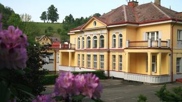 Un bâtiment jaune avec un toit rouge, de grandes fenêtres et un balcon.