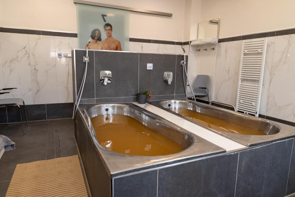 Un área de spa con dos tinas grandes llenas de agua, un perchero y un espejo.