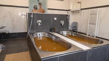 Un área de spa con dos tinas grandes llenas de agua, un perchero y un espejo.