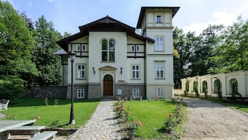 Stately building with a central entrance and arched windows, set amidst a well-manicured lawn and cobblestone pathway.