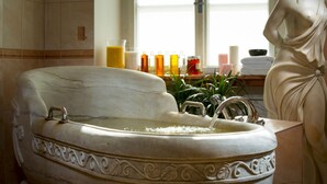 A marble bathtub with intricate carvings, a window with natural light, and a statue beside it. - Spa Resort Libverda - Villa Friedland (Lázne Libverda)