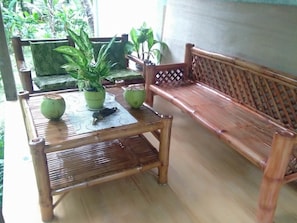 A wooden bench with a lattice backrest, a bamboo table with two potted plants, and a small decorative item. - Banaba Tree House (Samboan)
