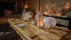 Una mesa de comedor de madera dispuesta con platos, cubiertos y faroles decorativos.