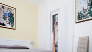 A hotel room with a bed, a chair, and two paintings on the walls. - BFAME - Cornice Barocca (Ragusa)