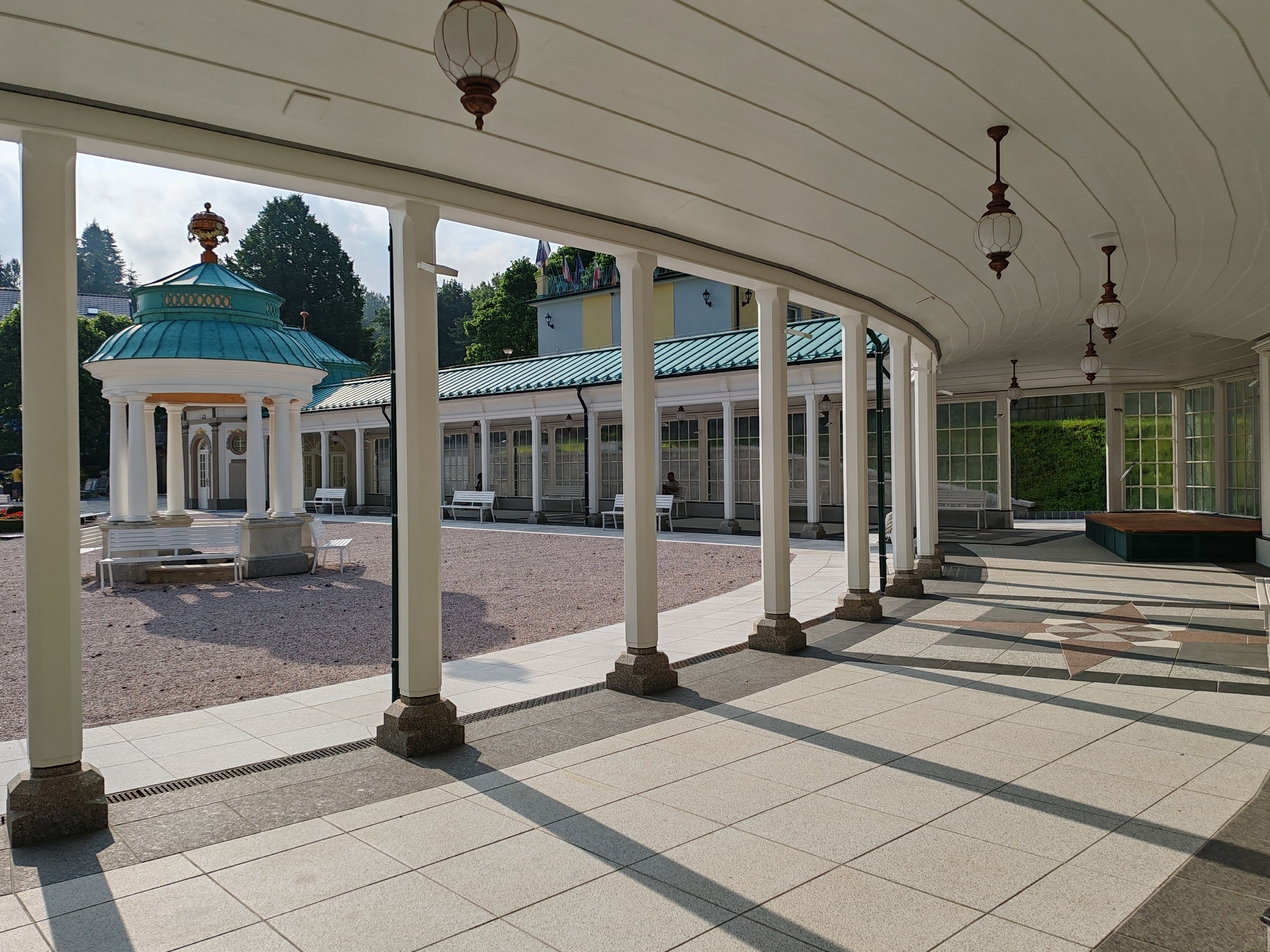 A covered outdoor area with a gazebo, benches, and a tiled floor.