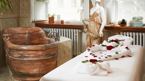 Une salle de bain avec une grande baignoire décorée, une coiffeuse avec un miroir et une statue.