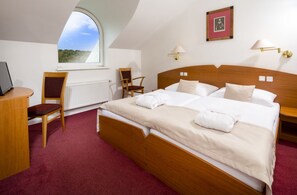 A hotel room with a large bed, two chairs, a desk, a window with a view, and a framed picture on the wall. - Spa Resort Libverda - Nový Dům (Lázne Libverda)