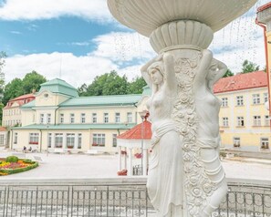 Estátua clássica com esculturas detalhadas em uma praça pública.