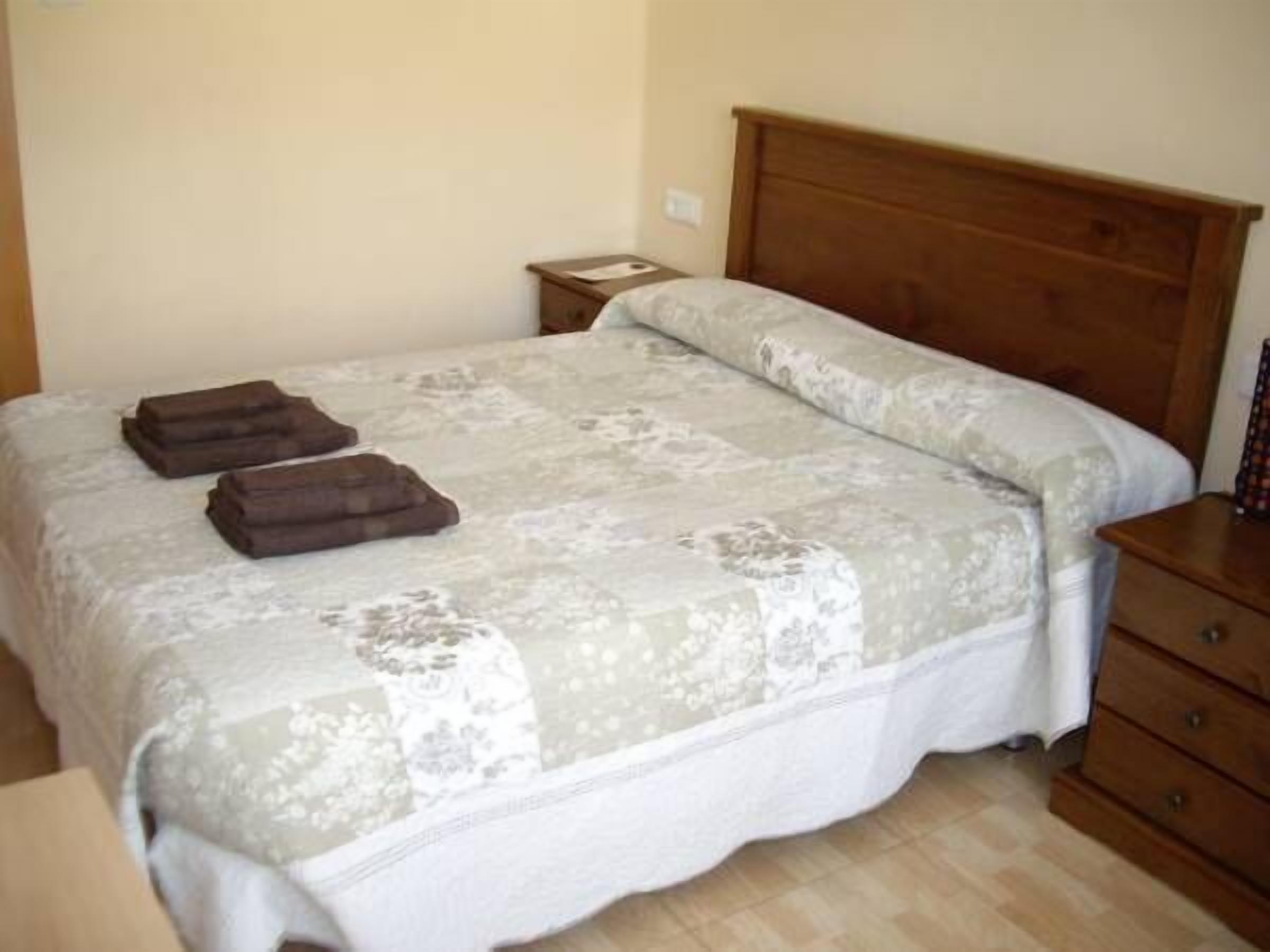 Un dormitorio con cama, mesita de noche de madera y cómoda.