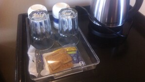 Una bandeja con una cafetera, dos tazas y una pequeña caja de pañuelos.