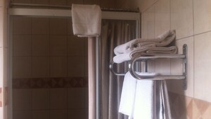 Un baño con ducha, un perchero con toallas dobladas y una cortina de ducha.