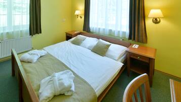 A hotel room with a large bed, two bedside tables, a chair, and two lamps.