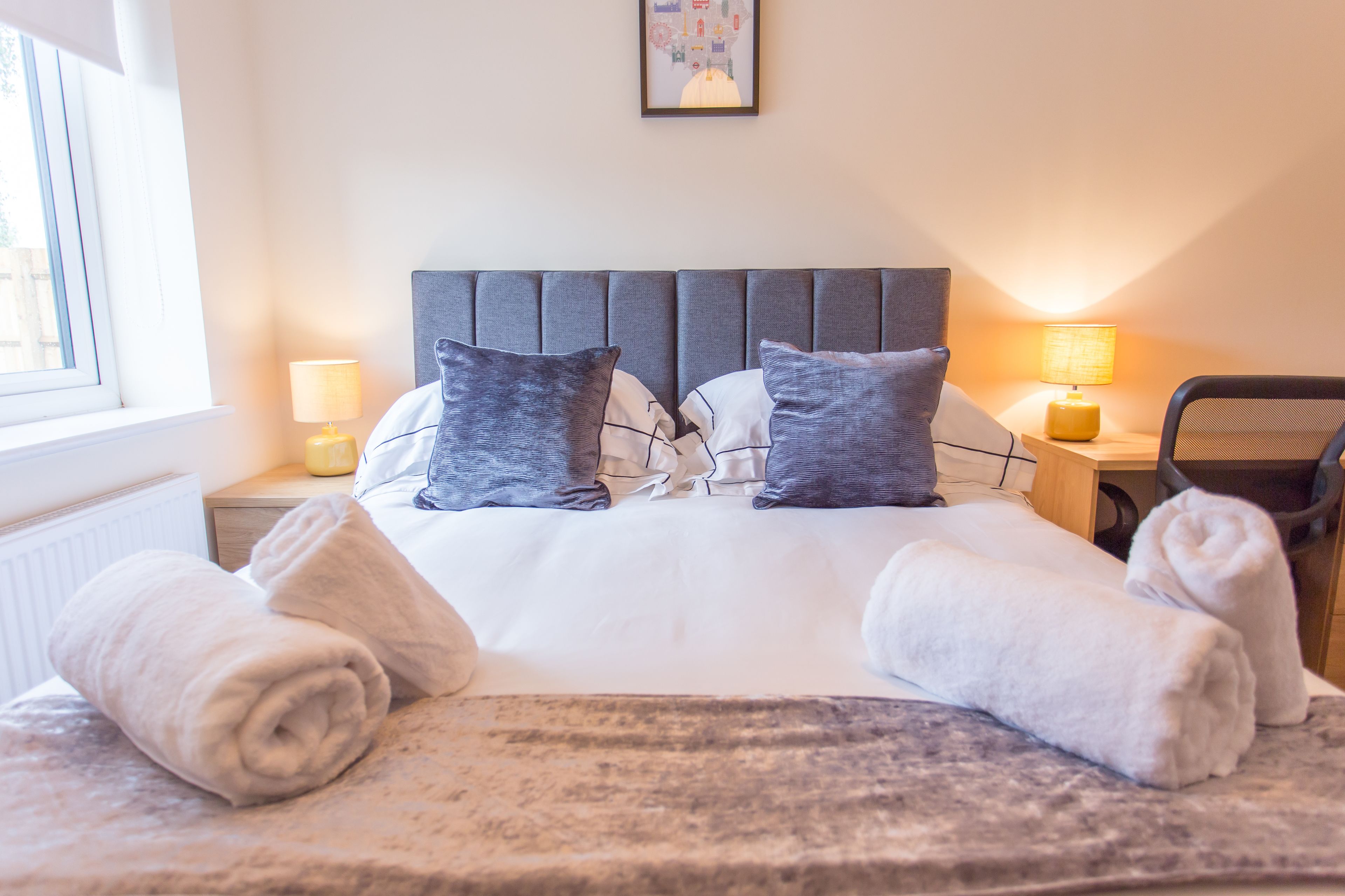 A neatly made bed with pillows, a headboard, and two bedside lamps.
