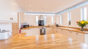 A modern kitchen with a wooden countertop, stainless steel appliances, and white cabinetry. - Razia Apartments (Oxford)