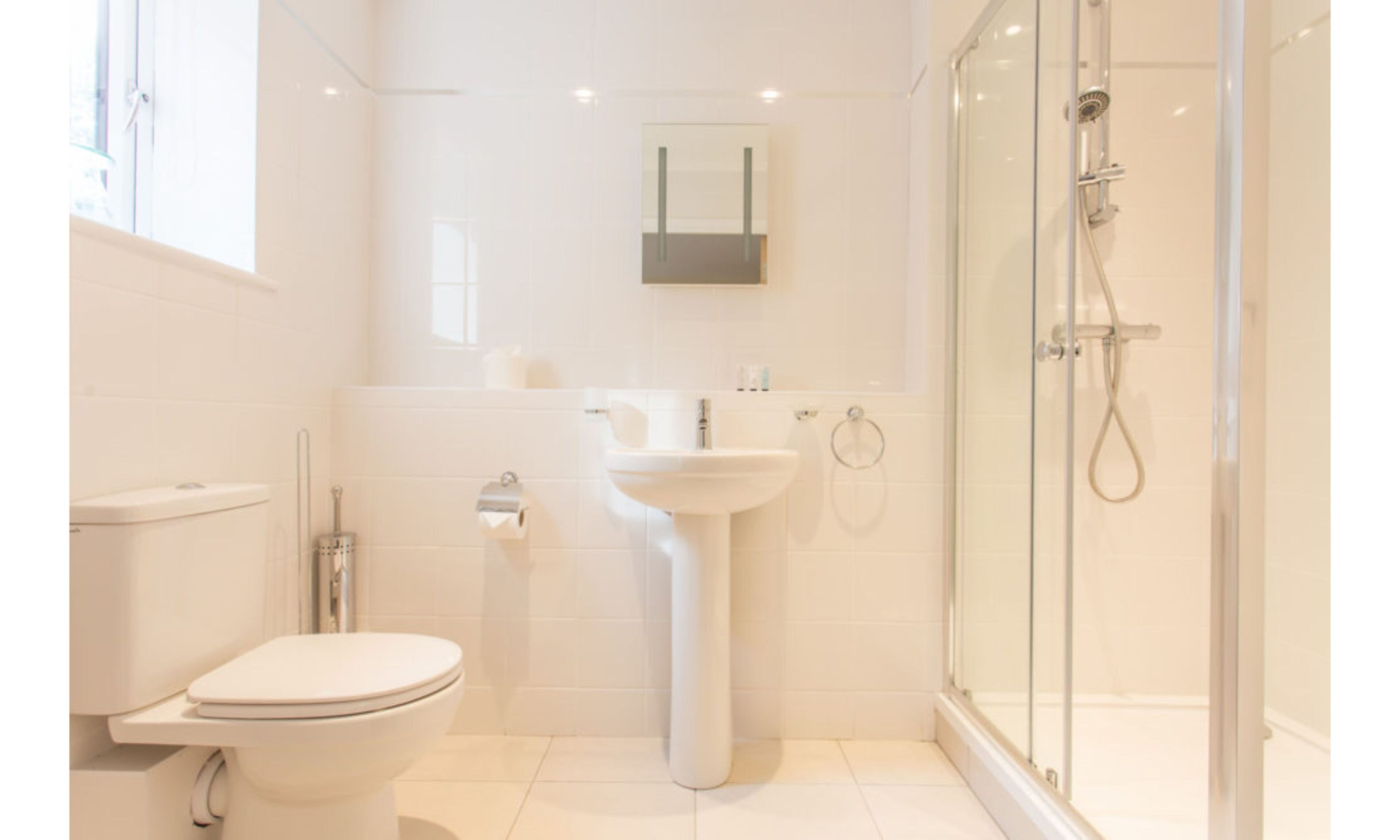 Une salle de bain moderne équipée de toilettes, d’un lavabo et d’une douche à parois de verre.