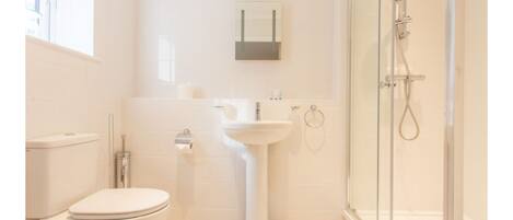 Une salle de bain moderne équipée de toilettes, d’un lavabo et d’une douche à parois de verre.