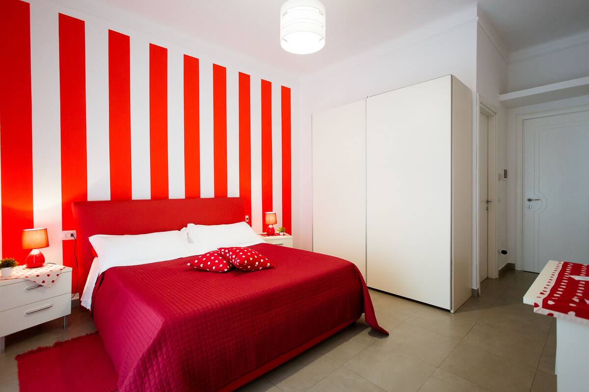Una habitación con cama, mesitas de noche, un armario y una puerta.