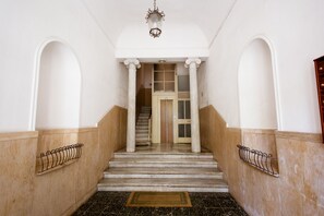 Eine imposante Treppe mit weißen Säulen und Holzvertäfelung, die zu einer Tür mit Glasscheiben führt.